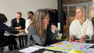 Deltagere rundt om et bord til Design, Strategi & Organisation