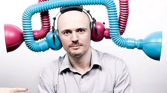 Man wearing ear defenders surrounded by flexible blue and pink tubes.
