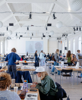 Studerende arbejder ved borde i en stor, lys atelierhal.