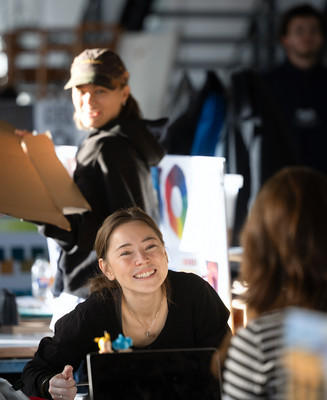 Studerende samarbejder ved arbejdsborde i et lyst designstudio.