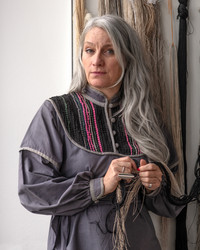 Female researcher in grey dress standing in front of wall of yarn samples