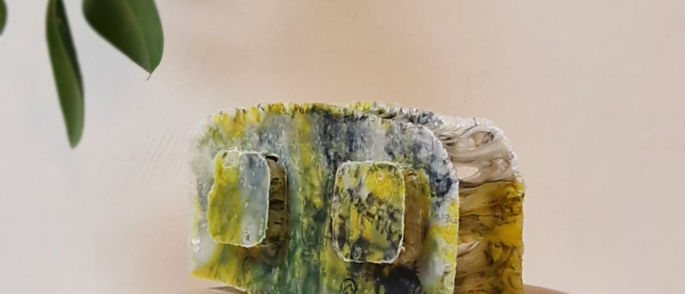Small textured lump in yellow and green on a wooden stool.