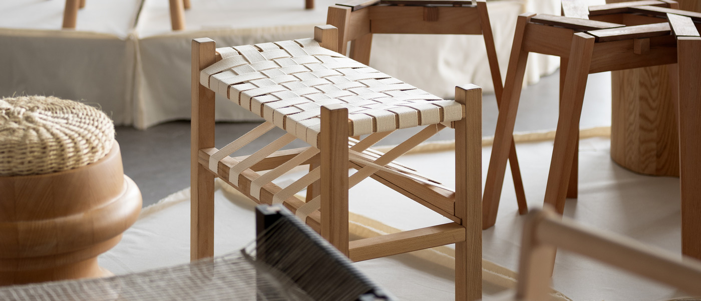 Exhibition of wooden stools and seating designs on plinths.