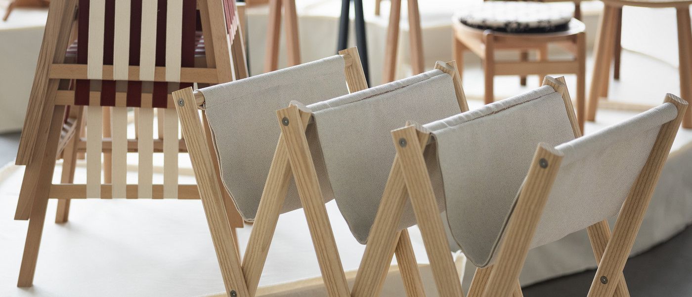 Foldable wooden chairs displayed on an exhibition platform.