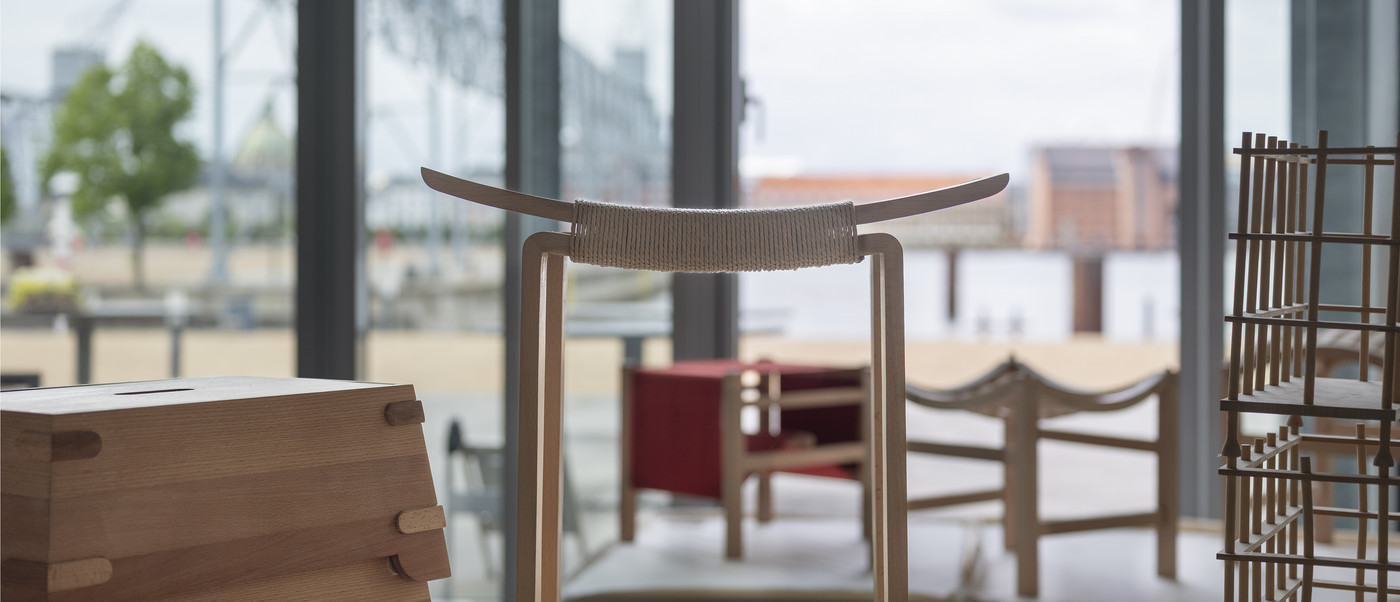 Wooden stool and small furniture pieces by a window.