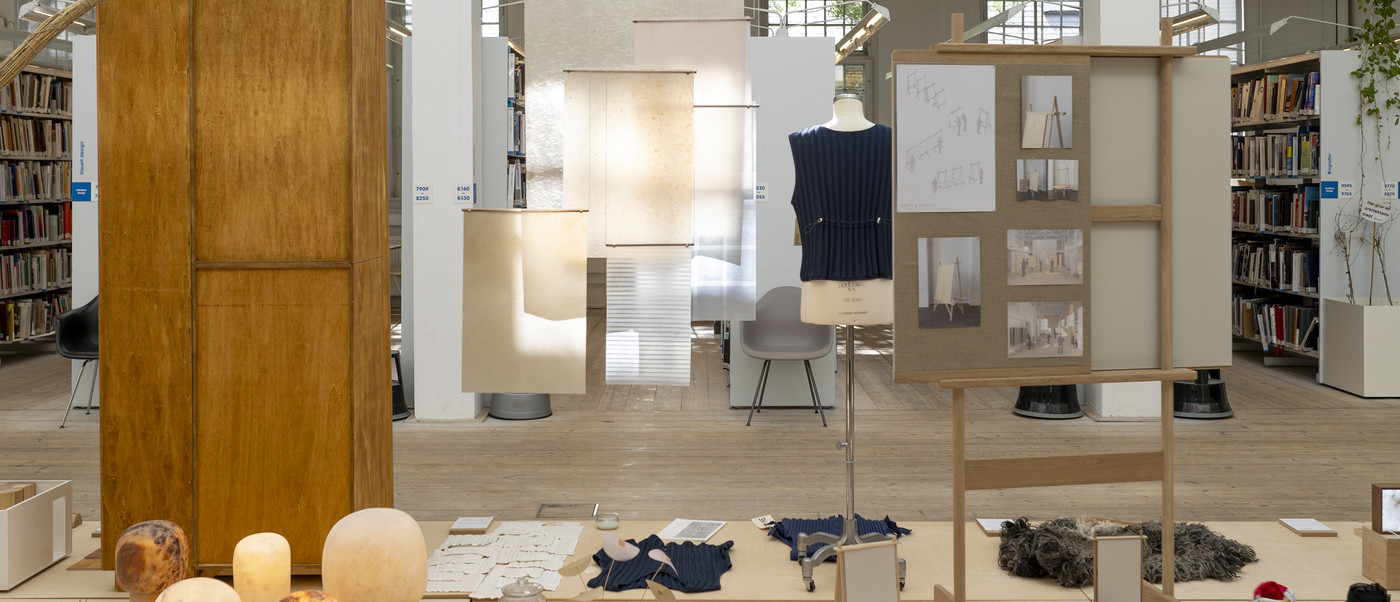 Library exhibition with hanging material samples, mannequin, and display boards