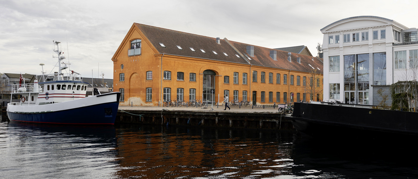 Harbor with boat and orange industrial building.