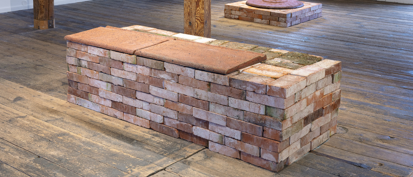 Brick installation in gallery space on wooden floor.