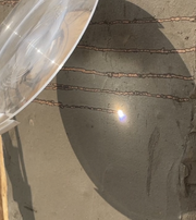 Lens focusing sunlight on a wall with horizontal markings.