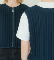 Two people wearing dark vests, shown from the front and back.