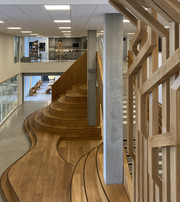 Moderne indendørs atrium med trappe i træ og åbne etager