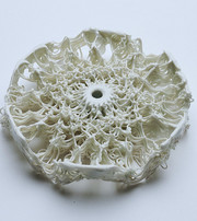 White 3D-printed lattice structure with raised, tangled strands and a central hole.