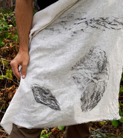 Person holding white fabric with black prints of rocks and natural textures.