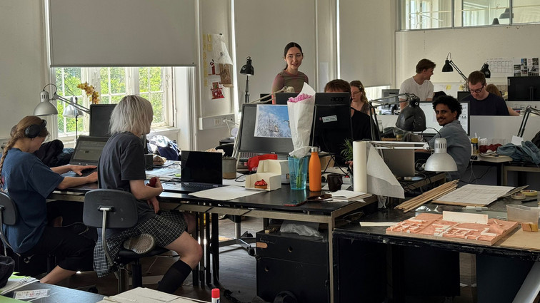 Design studio with people working at desks with computers and models.