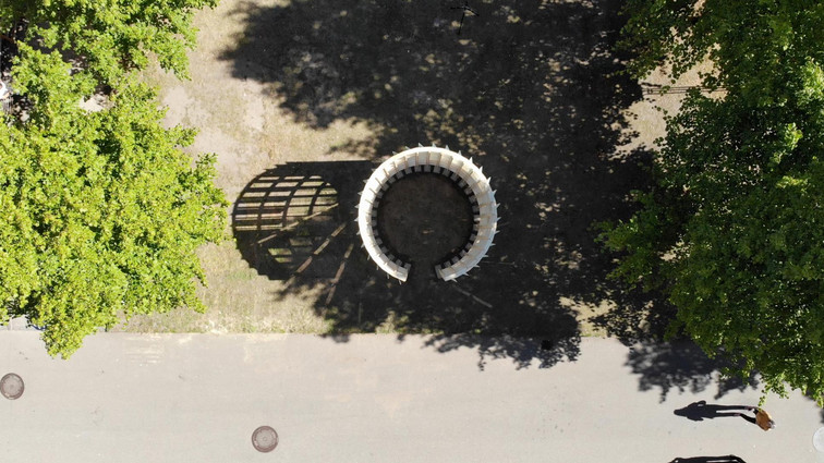 Aerial view of a circular wooden pavilion among large trees.