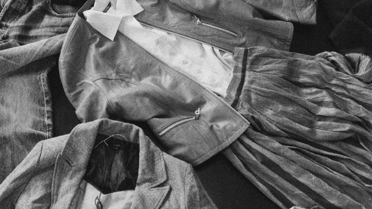 Assorted jackets, shirts and trousers arranged in an overlapping composition.