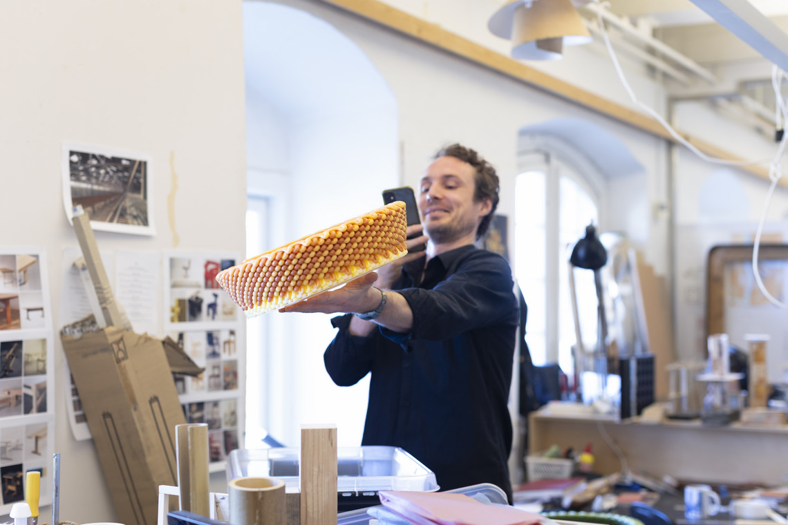 Person photographing a colorful circular design object in a studio.