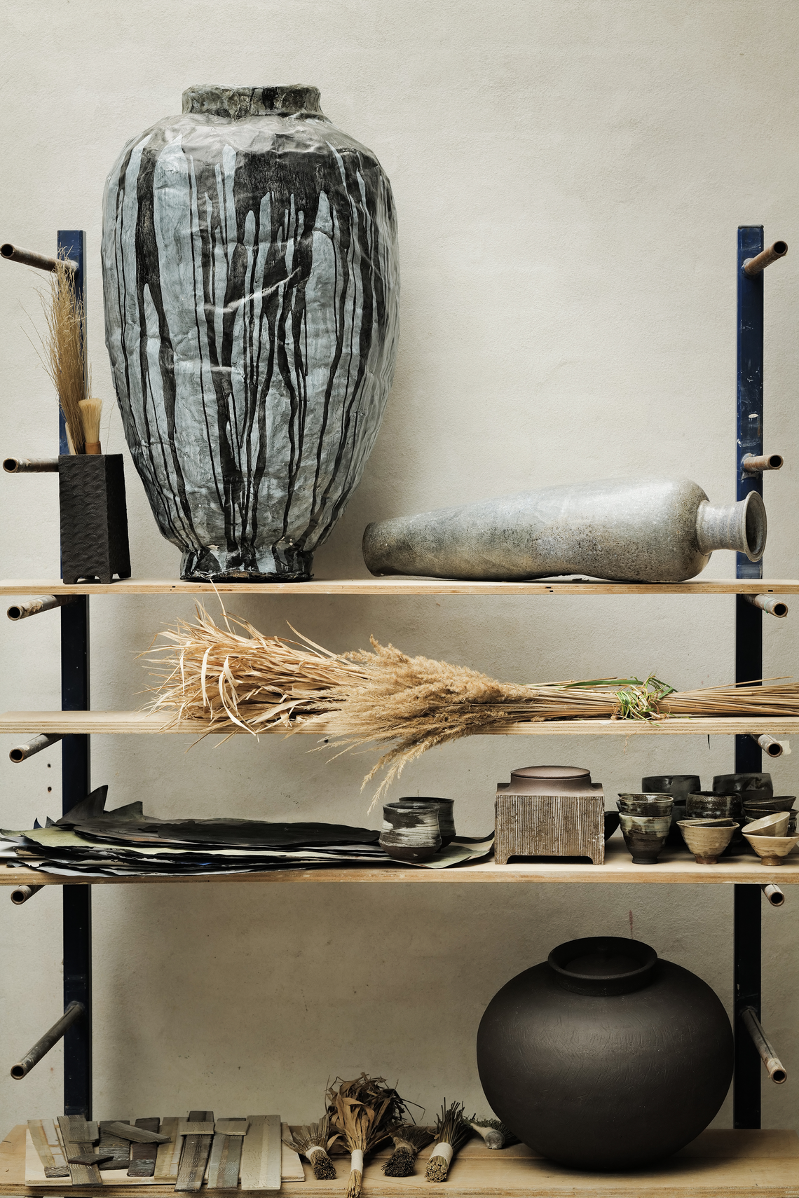 Shelves displaying handmade ceramic vessels, tools, and materials.