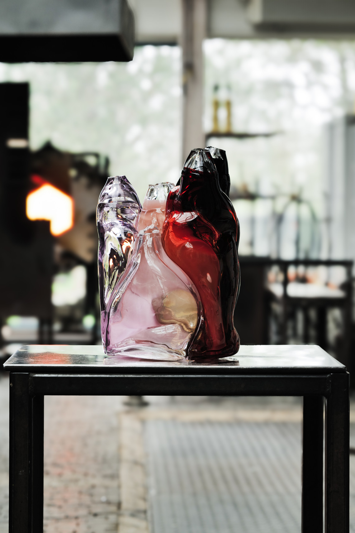 Colored glass sculpture displayed on a table in a studio.