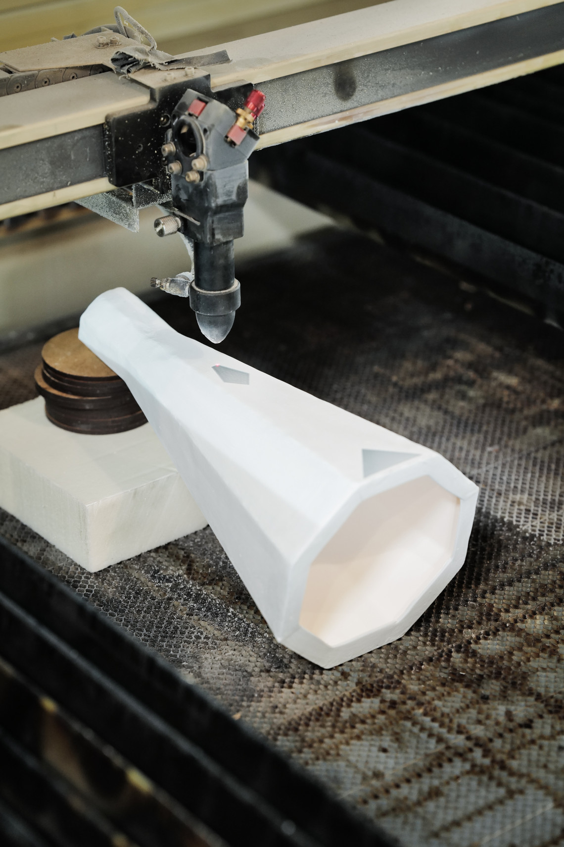 Laser cutting machine shaping a white object in a workshop