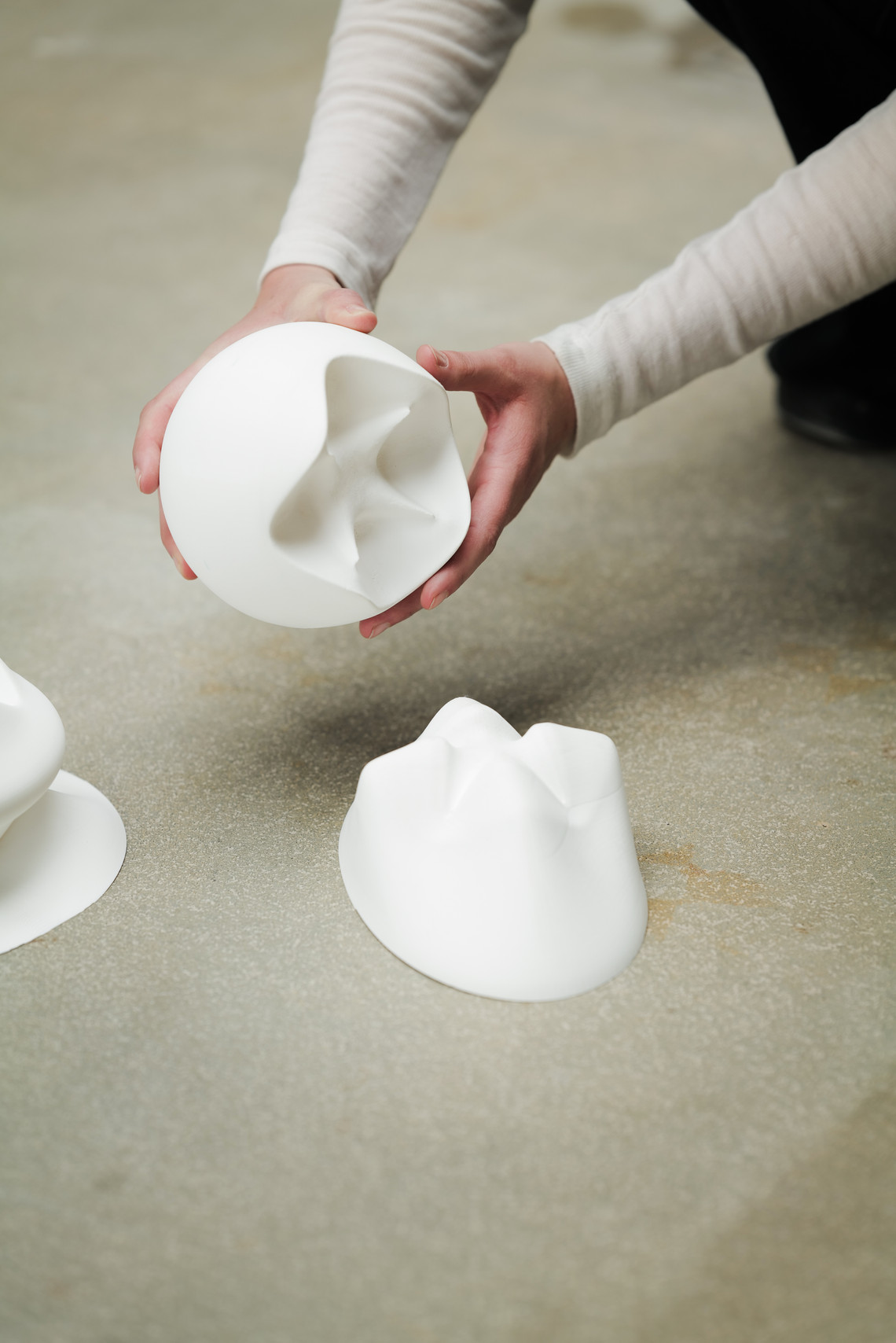 Hands holding a white, organically shaped sculpture.