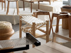 Exhibition of wooden stools and seating designs on plinths.