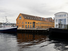 Harbor with boat and orange industrial building.