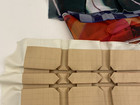 Layered colorful fabric samples above folded paper prototypes on a work surface.