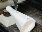 Laser cutting machine shaping a white object in a workshop