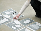 Person arranging printed images of shapes on the floor.