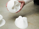 Hands holding a white, organically shaped sculpture.