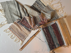 Handwoven textile samples next to a loom