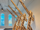 Large installation of angled timber structures with intersecting beams in an exhibition hall.