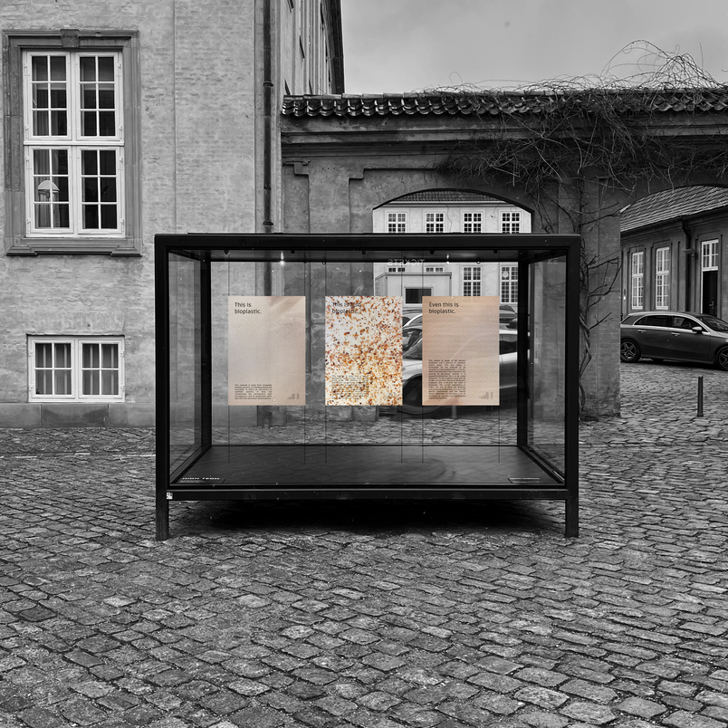 Exhibition cabinet showing three posters in earth tones
