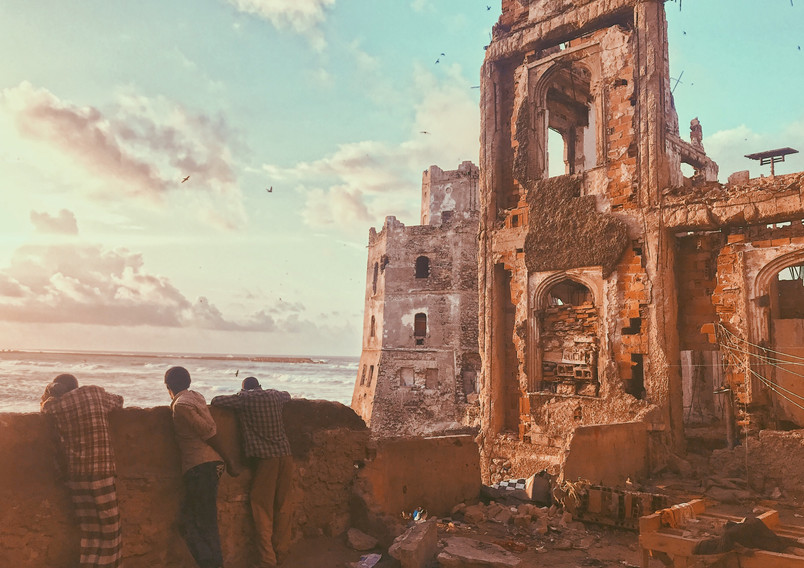 Coastal ruins with three people looking at the sea.