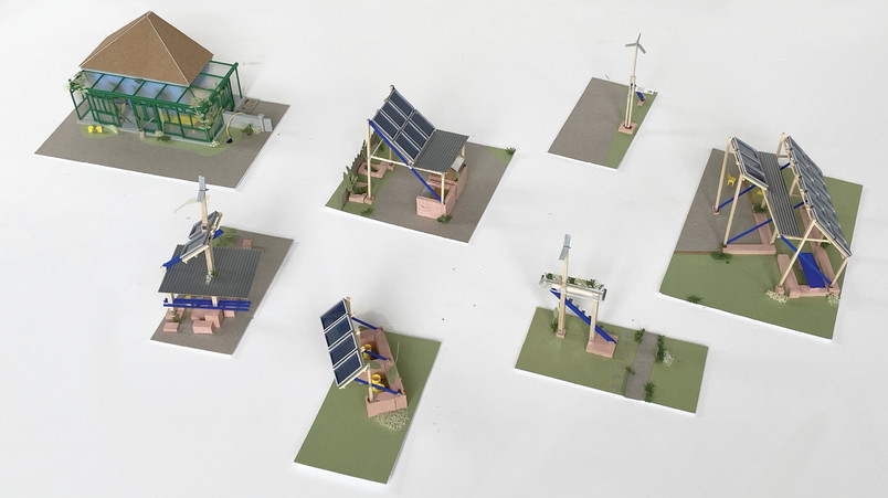 Small architectural models with solar panels and wind turbines on green bases.