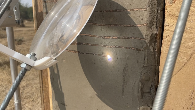 Lens focusing sunlight on a wall with horizontal markings.