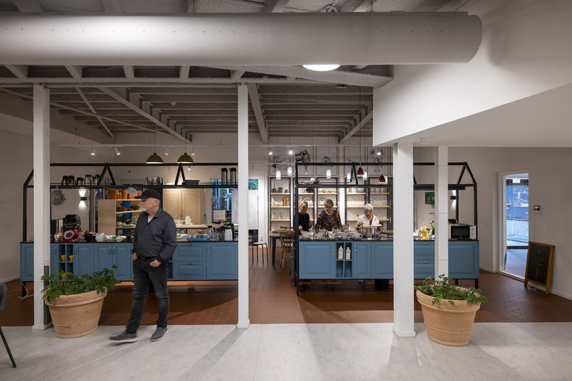  Shared kitchen with several people, kitchen islands, blue cabinets, and utensils on open shelves