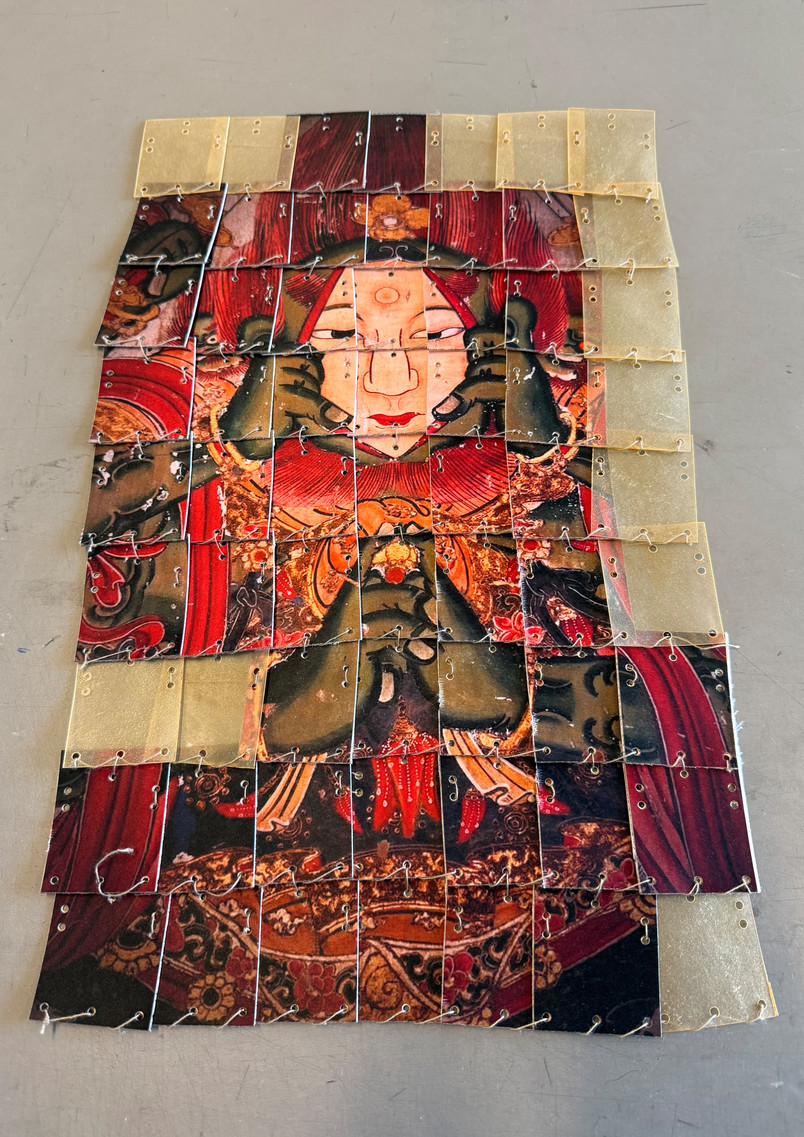 Textile sample integrating the image of the Face-Tearing Wisdom King into an armour-inspired construction, where fragmented and reconstructed layers translate temple imagery into a protective surface.