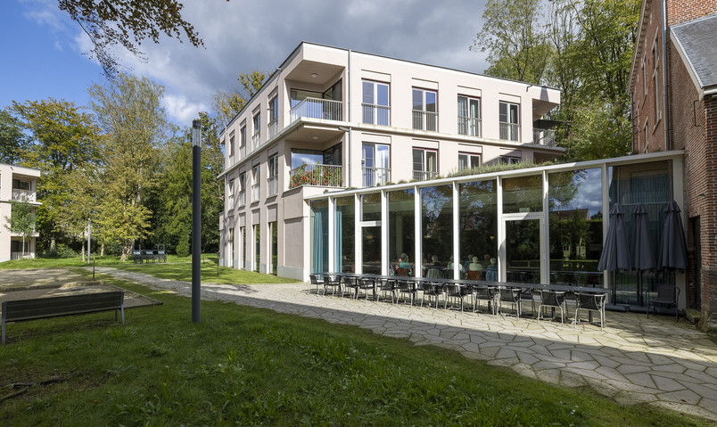 Modern residential building with glass façade and terrace in green surroundings