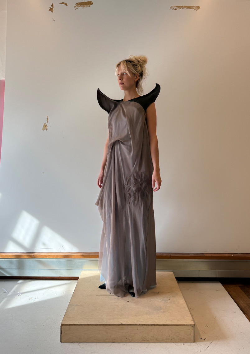 Model wearing a grey translucent garment inspired by incense smoke, with curved eave-like structures extending around the upper body.