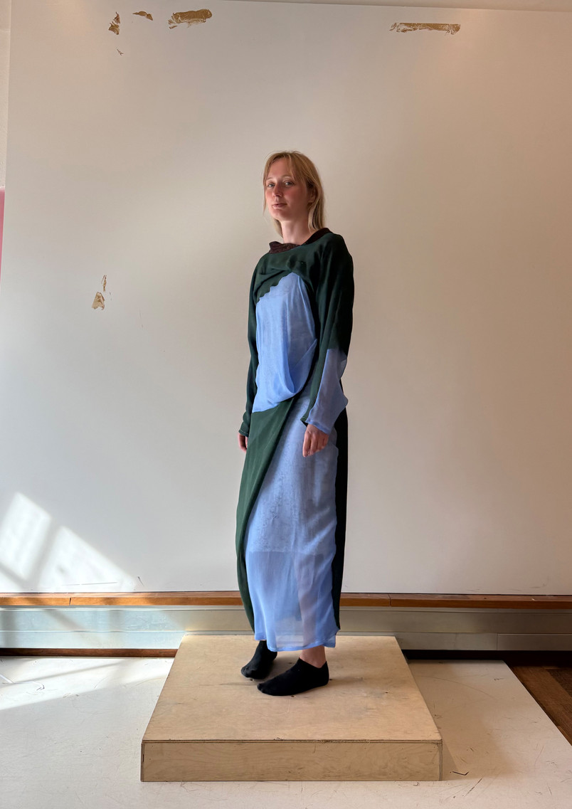 Model wearing a blue and green layered garment inspired by flowing incense smoke, where soft layers wrap, blur, and move around the body.