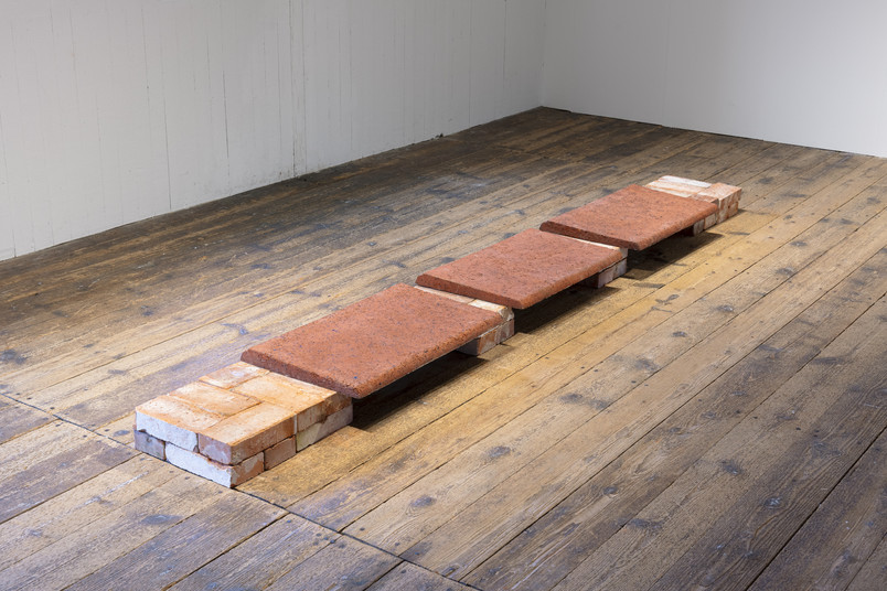 Low bench made of bricks and red tiles on a wooden gallery floor