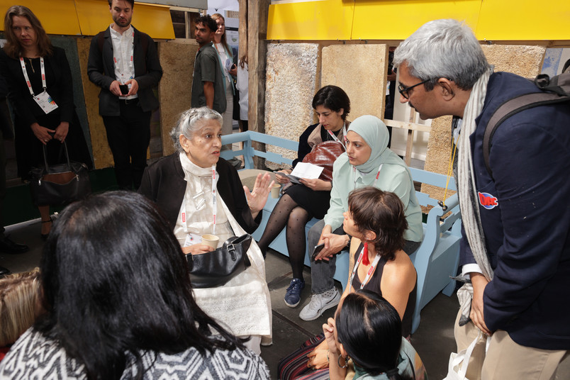 Woman surrounded by people whom she is speaking to 
