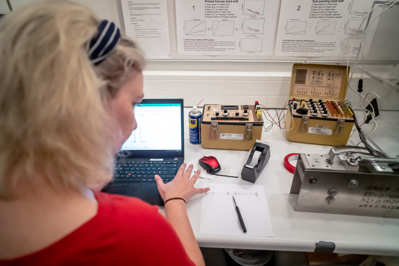 Person works at a computer among measuring and experimental equipment in a laboratory.