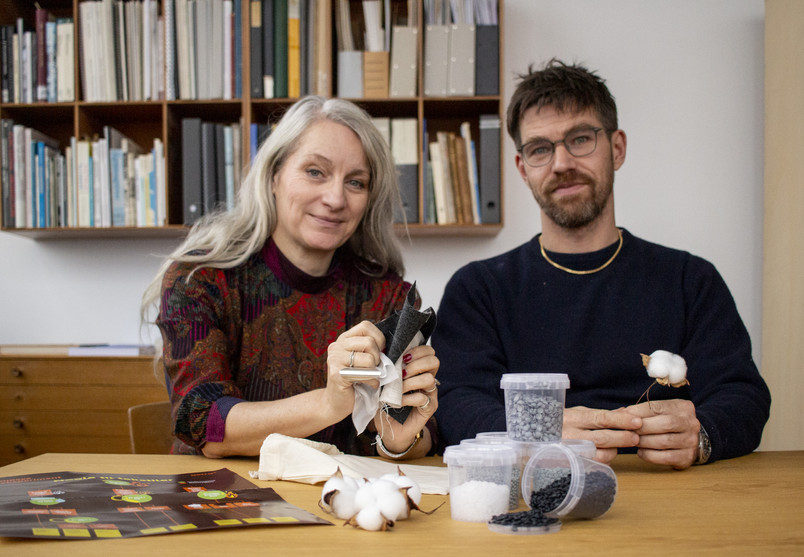 Two people sitting by a table with a series of objects lying in front of them