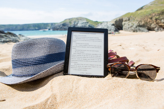 E-bog, solbriller og sommerhat på stranden