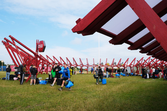 Red support beams in a circular structure. Festival guests are arriving