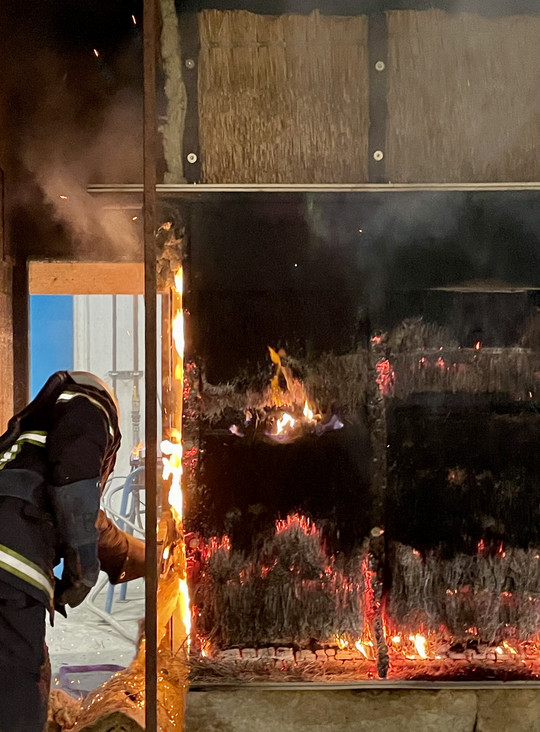 Fire affecting a vertically thatched façade.