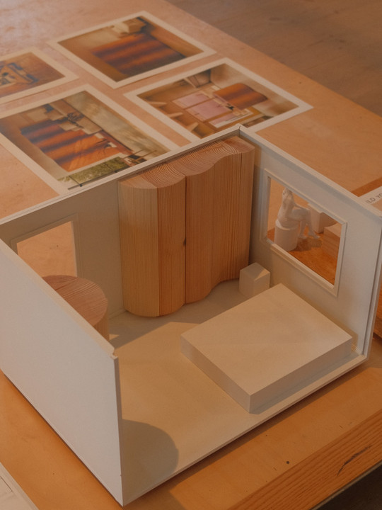 Architectural model with wooden elements and images in the background.